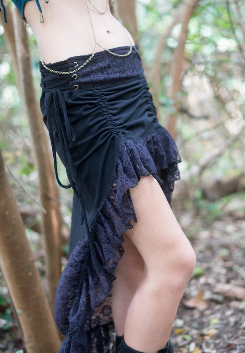 May include: A black skirt with a lace overlay and a high-low hemline. The skirt is gathered at the waist and has a drawstring closure.