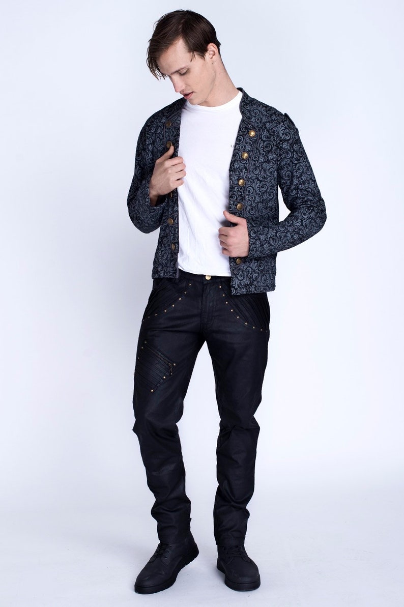 Puede incluir: Un hombre con una chaqueta de patr&oacute;n azul oscuro con botones dorados, pantalones vaqueros negros con detalles dorados y zapatos negros.