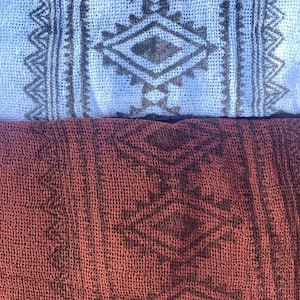 May include: Two pieces of fabric with a geometric pattern. The top piece is light blue with a dark gray pattern. The bottom piece is a dark red with a dark gray pattern.