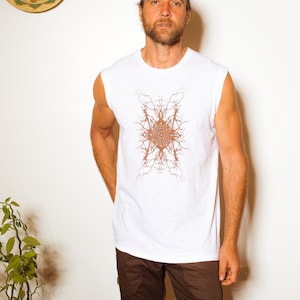 May include: A white sleeveless shirt with a brown geometric design. The shirt is worn by a person with brown hair and a beard. The person is wearing brown shorts.