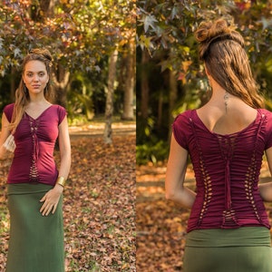 May include: A maroon top with a lace-up back detail and short sleeves. The top is paired with a dark green skirt.