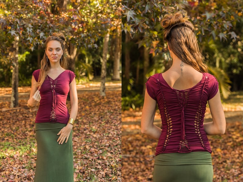 May include: A maroon top with a lace-up back detail and short sleeves. The top is paired with a dark green skirt.