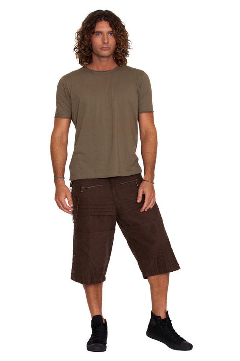 May include: A man is wearing a brown t-shirt and brown cargo shorts with multiple pockets. He is wearing black high-top sneakers.