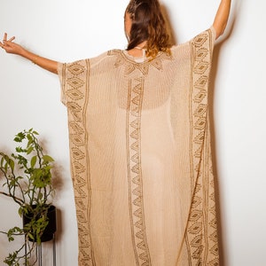 Puede incluir: Una larga kaft&aacute;n beige y transparente con un patr&oacute;n geom&eacute;trico marr&oacute;n. La kaft&aacute;n tiene un corte holgado y fluido, ideal para superponer.