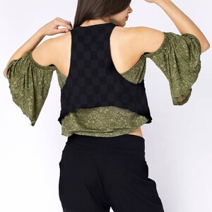 May include: A black and green sleeveless top with a checkered pattern. The top has a scoop neck and a cropped hem. The model is wearing black pants with a wide leg.