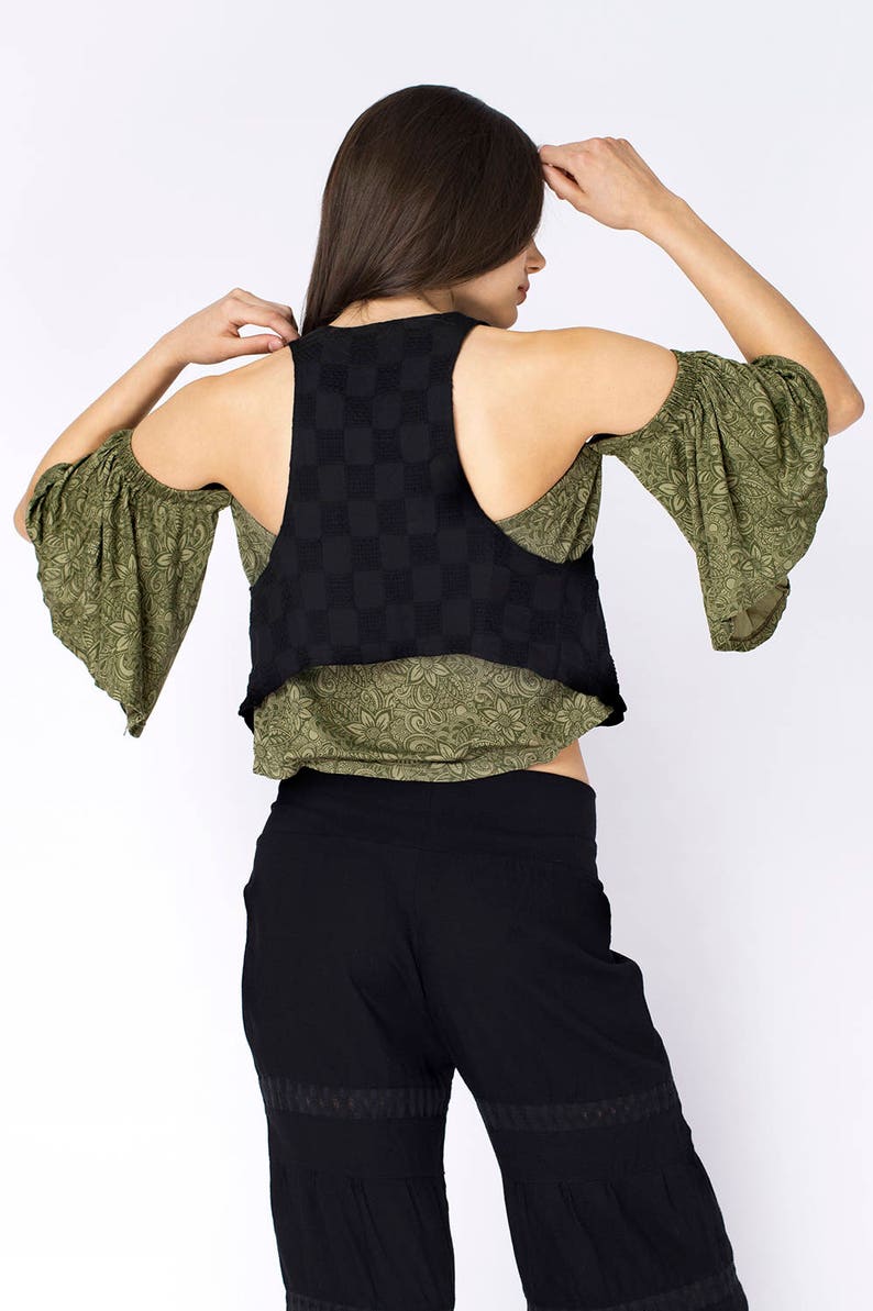 May include: A black and green sleeveless top with a checkered pattern. The top has a scoop neck and a cropped hem. The model is wearing black pants with a wide leg.