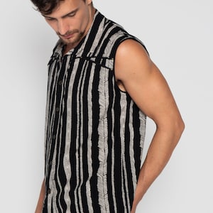 May include: A sleeveless button-up shirt with a black and white striped pattern. The shirt has a collar and a button closure.