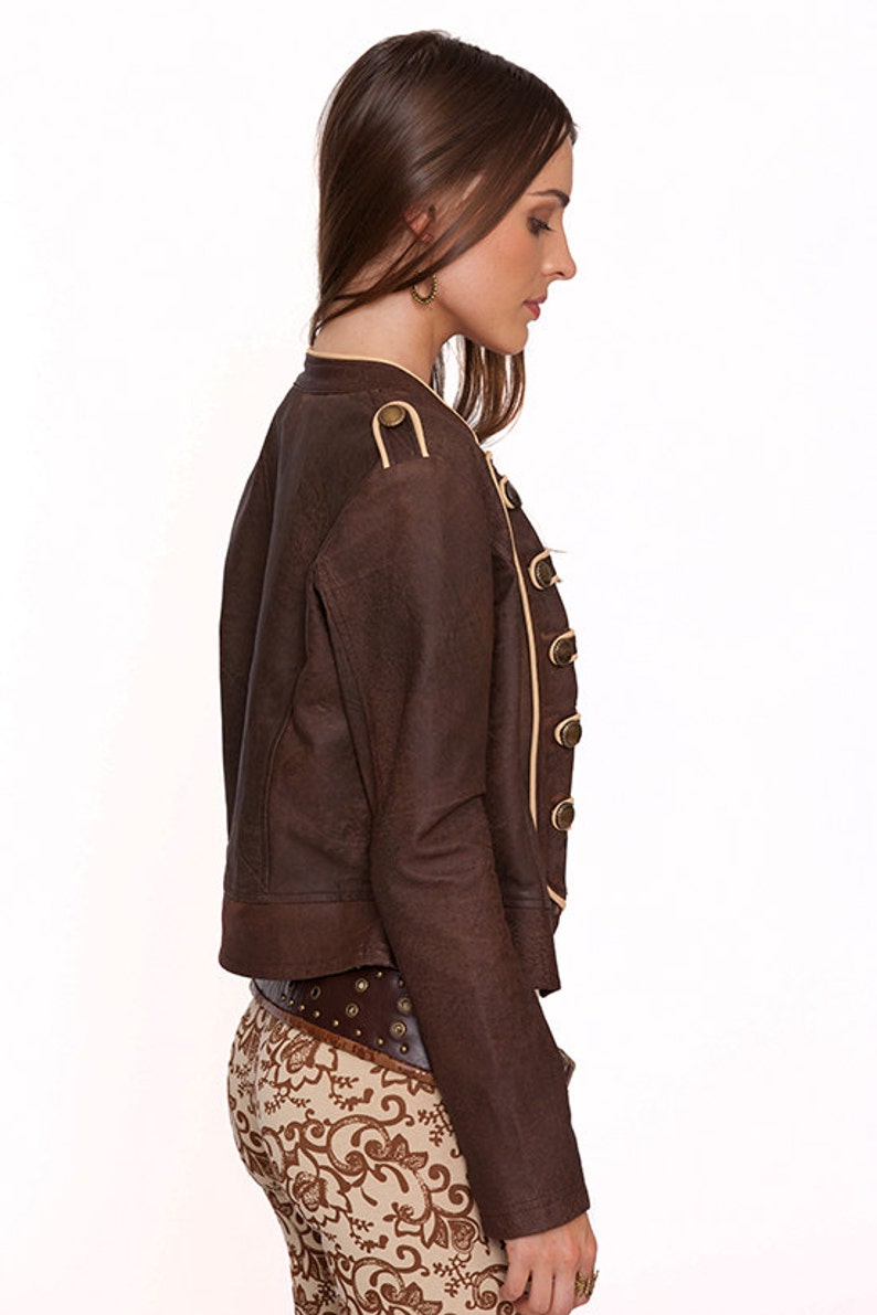 May include: A brown leather jacket with a cream trim and gold buttons. The jacket has a cropped length and a fitted silhouette.