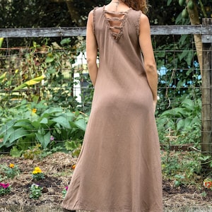 May include: A brown sleeveless maxi dress with a distressed back detail. The dress is made of a soft, flowing fabric and has a relaxed fit.