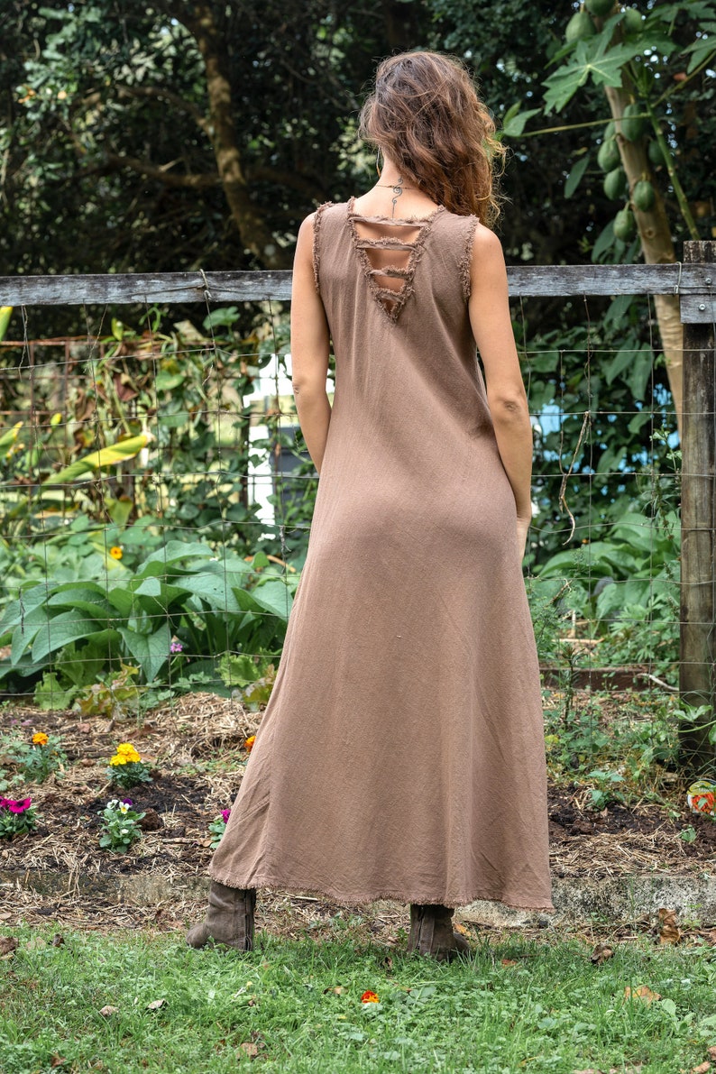 May include: A brown sleeveless maxi dress with a distressed back detail. The dress is made of a soft, flowing fabric and has a relaxed fit.