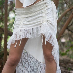 May include: A white lace and cotton skirt with a high-low hemline. The skirt has a drawstring waist and a lace overlay.