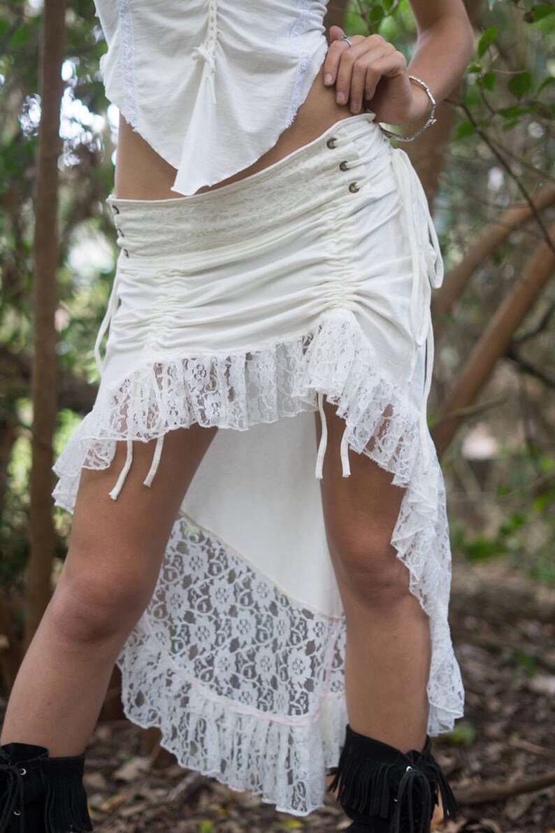 May include: A white lace and cotton skirt with a high-low hemline. The skirt has a drawstring waist and a lace overlay.