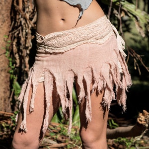 May include: A light pink skirt with a frayed hem and a white lace waistband. The skirt is made of a soft, flowing fabric and has a bohemian style.