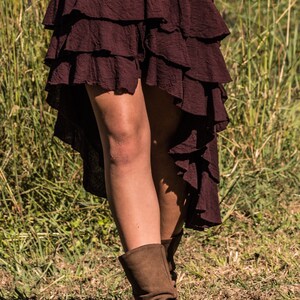 May include: A burgundy tiered skirt with a high-low hemline. The skirt is made of a soft, flowing fabric and has a casual, bohemian style.