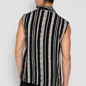 May include: A sleeveless shirt with a black and white striped pattern. The shirt has a button-up collar and a relaxed fit.
