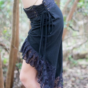 May include: A black skirt with a lace ruffle hem and a lace panel at the waist. The skirt has a drawstring closure and is tied at the side.
