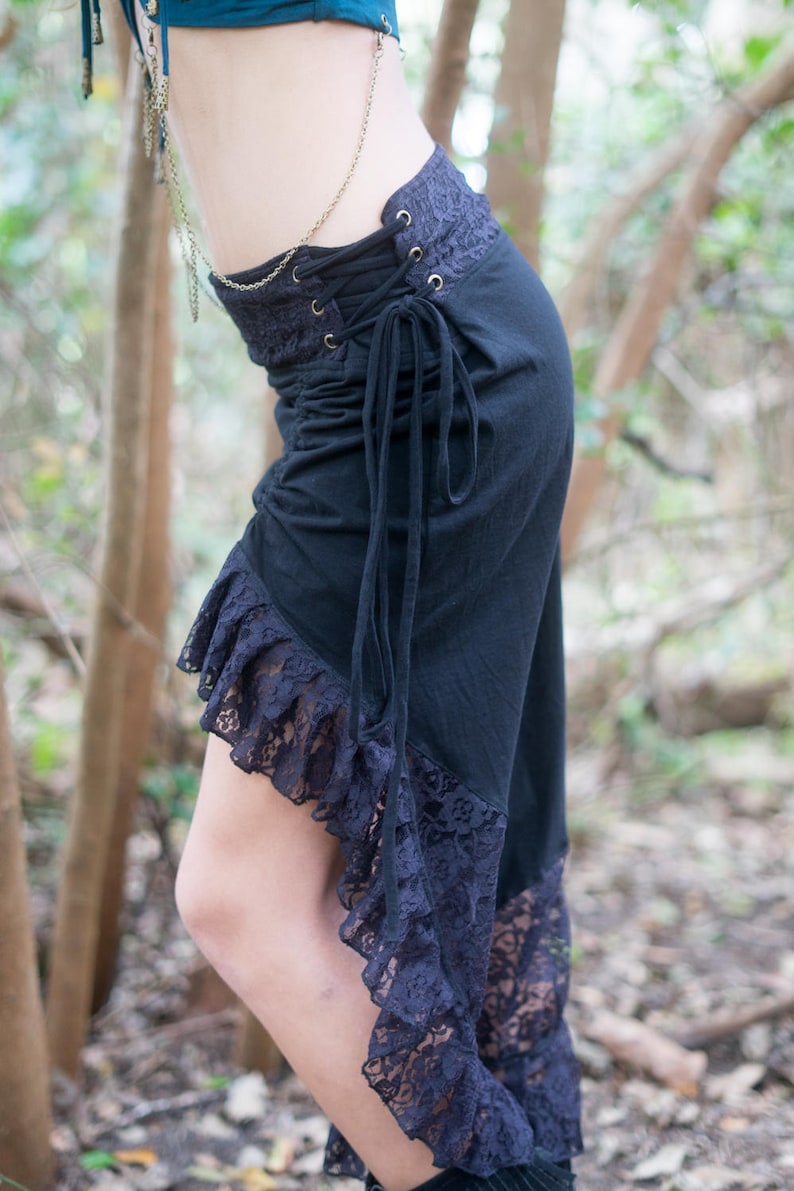 May include: A black skirt with a lace ruffle hem and a lace panel at the waist. The skirt has a drawstring closure and is tied at the side.