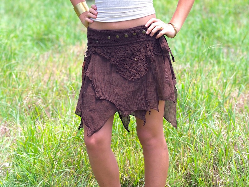 May include: A brown, asymmetrical skirt with a crocheted overlay and a brown leather belt with metal accents.