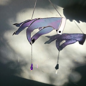 May include: A stained glass hand with a purple and blue gradient, hanging from a silver chain with a purple crystal pendant.