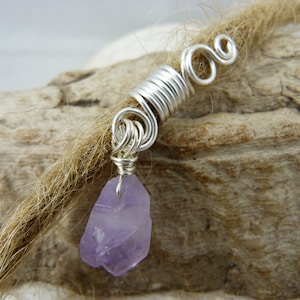 Op de afbeelding: Zilveren dreadlock-kraal met een paarse amethiststeen eraan bevestigd.