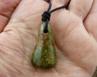 May include: A green and brown stone pendant with a black cord necklace. The stone has a speckled pattern.