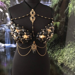 May include: A black bra decorated with gold and black seashells, with a gold chain and black bead necklace.