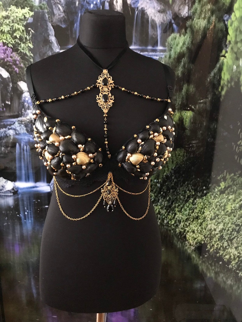 May include: A black bra decorated with gold and black seashells, with a gold chain and black bead necklace.