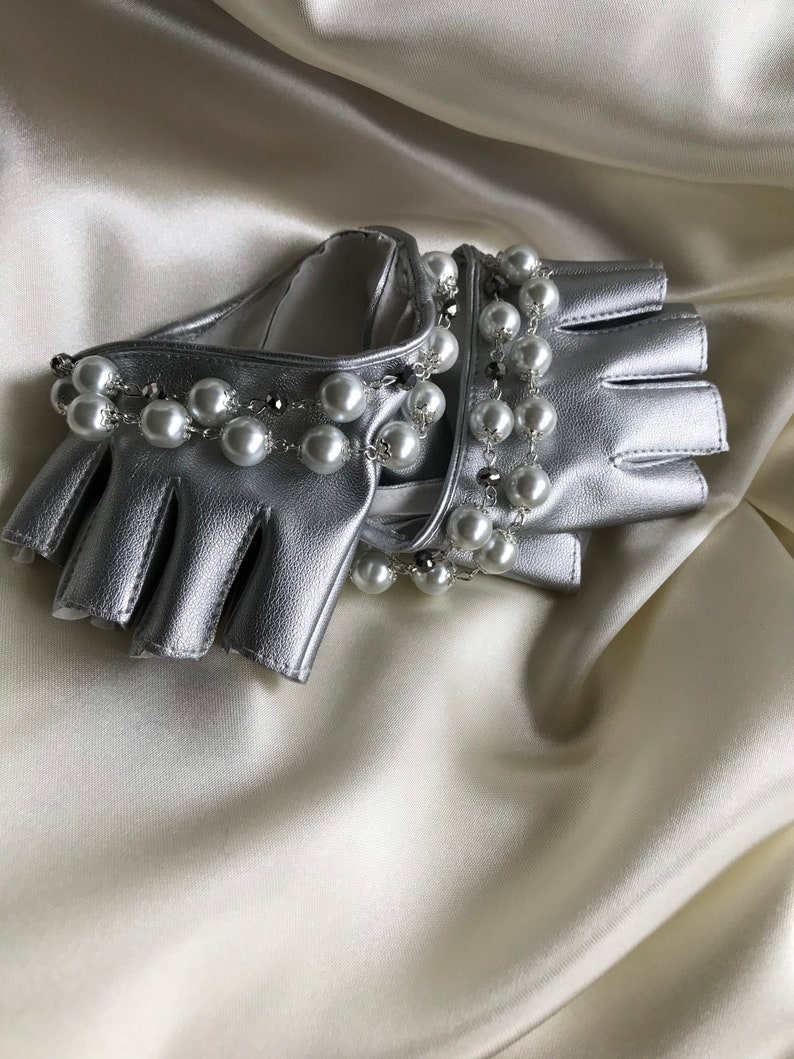 May include: Silver leather fingerless gloves with a pearl and chain embellishment.