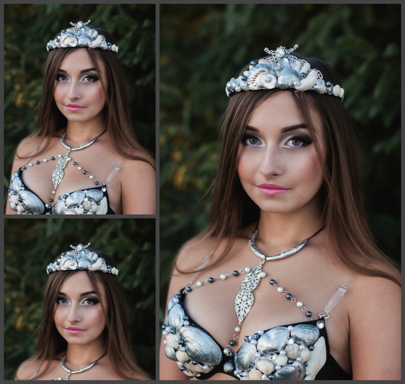 May include: A woman wearing a silver and white seashell crown and a silver and white seashell bra. The bra has a silver chain with a pendant in the shape of a seashell. The woman is wearing a black top and has long brown hair.