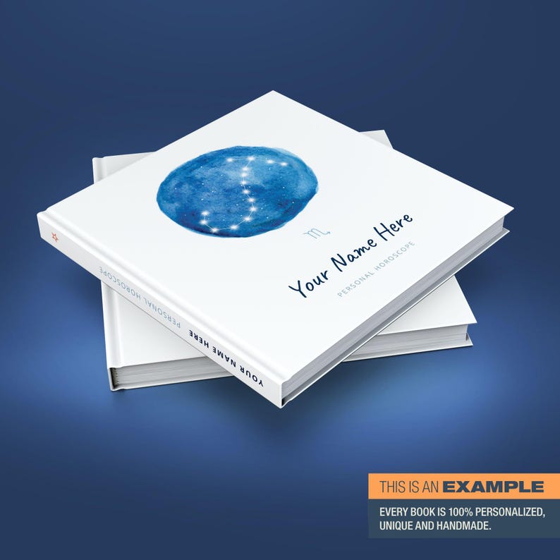 May include: A white book with a blue watercolour illustration of the Sagittarius constellation. The book has the text "Your Name Here" and "Personal Horoscope" on the cover.