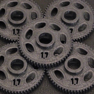 May include: Five gray plastic gears with 17 teeth each. The gears are interlocked and arranged in a circular pattern.