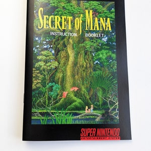 Pode incluir: Um livreto de instruções preto para o jogo Super Nintendo "Secret of Mana". A capa apresenta uma ilustração vibrante de uma floresta exuberante com uma grande árvore, duas figuras e o título do jogo em amarelo.