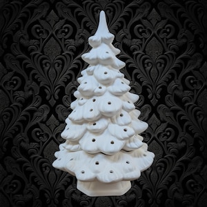 May include: A matte white ceramic Christmas tree figurine featuring a tiered, conical shape with numerous small, circular openings distributed across the branches, resting on a sturdy, integrated base with a smooth, unpainted surface finish.