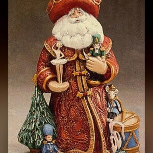May include: A decorative Santa Claus figurine, approximately 10 inches tall, in a red and gold robe, holding a ballerina and a nutcracker. The figurine has a white beard and a red hat. A Christmas tree, a drummer boy, and a mouse are also featured.