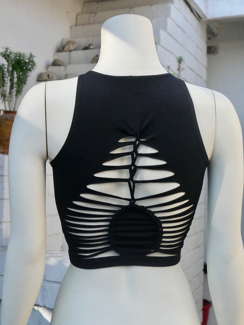 May include: Black sleeveless crop top with a unique criss-cross design on the back. The design features multiple cutouts and a woven pattern.