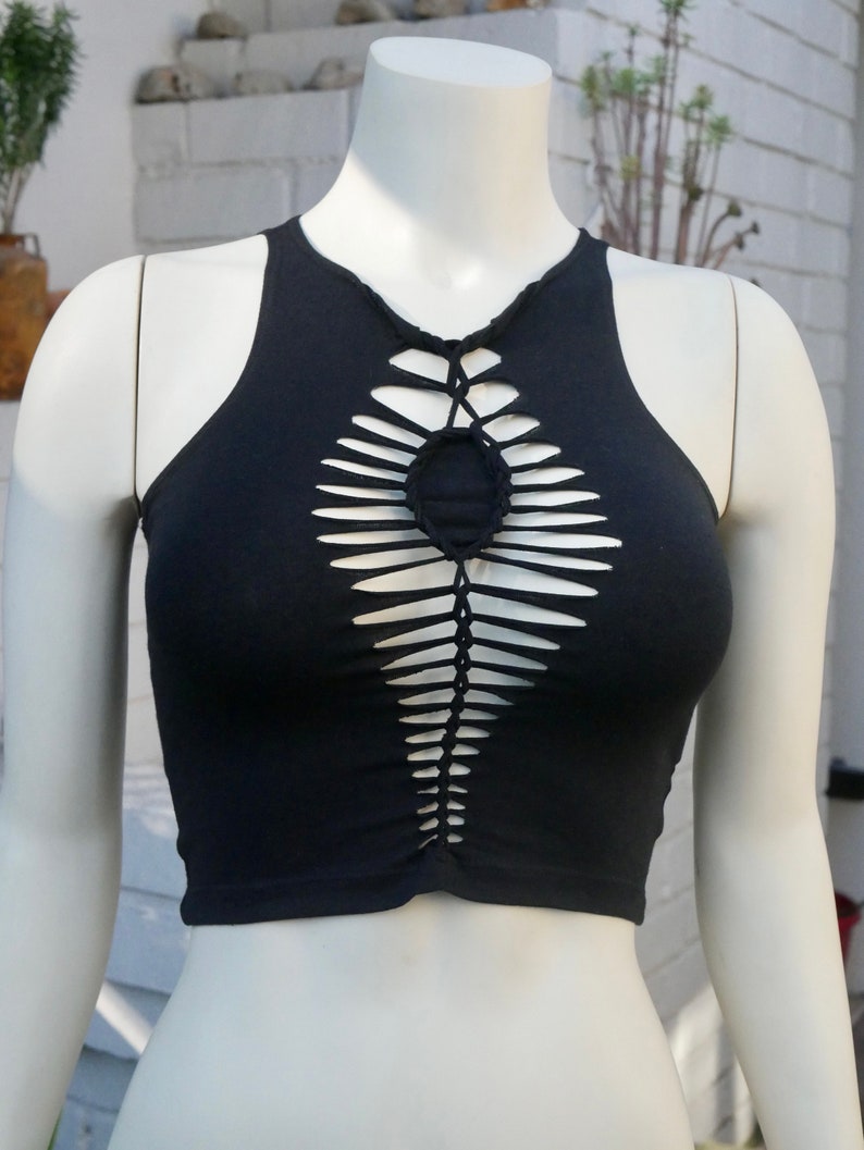 May include: A black crop top with a unique cut-out design featuring a braided pattern and a circular opening at the center.