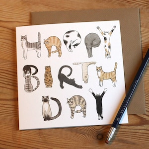 May include: A white card with a birthday greeting spelled out using illustrations of cats. The greeting reads "Happy Birthday".