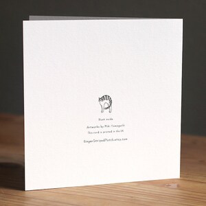 May include: A white card with a black and white illustration of a cat on the back. The text on the back reads "Blank inside", "Artwork by Miki Yamaguchi", "This card is printed in the UK", and "GingerStripedPatch.etsy.com".