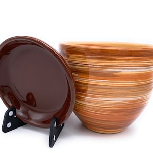 May include: A brown ceramic planter with a matching saucer. The planter has a striped design in shades of brown, orange, and white.