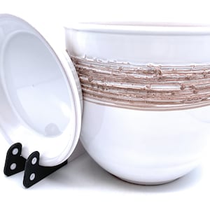 May include: White ceramic planter with a brown textured band around the middle. The planter has a matching lid.