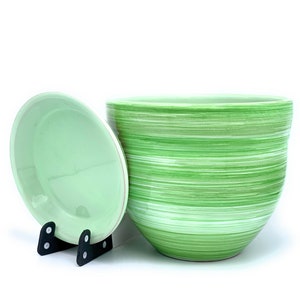 May include: A green and white striped ceramic planter with a matching saucer. The planter has a smooth, glossy finish and is ideal for adding a touch of nature to any home.