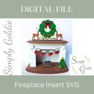 May include: A white wooden fireplace with a red and green Christmas wreath, stockings, and a small Christmas tree. The fireplace has a brown base and a white mantel with the words "Merry Christmas" in gold letters. The image is titled "Fireplace Insert SVG" and is from the shop "Simply Goldie".