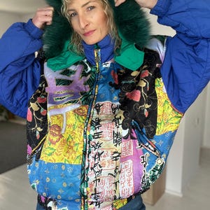 May include: A blue and green quilted jacket with a faux fur hood. The jacket has a patchwork design with Chinese characters and floral patterns.