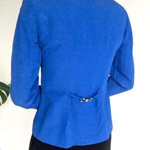 May include: A royal blue blazer with a single button closure at the back.