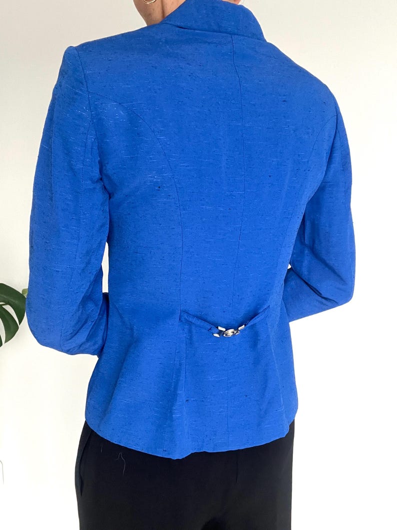 May include: A royal blue blazer with a single button closure at the back.