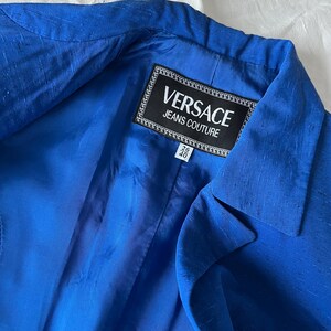 May include: A royal blue blazer with a black label that reads "VERSACE JEANS COUTURE" and a size tag that reads "26/40".