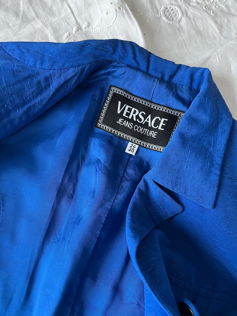 May include: A royal blue blazer with a black label that reads "VERSACE JEANS COUTURE" and a size tag that reads "26/40".