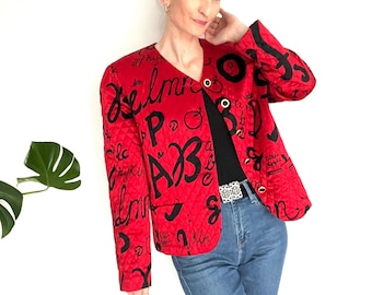 May include: A red quilted jacket with black lettering and a black and red trim. The jacket has a v-neck and a button closure.