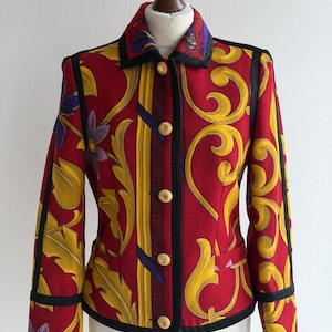 May include: A red jacket with a vibrant yellow and purple floral pattern. The jacket features black trim, gold buttons, and a classic collar. The design includes a vertical stripe with a geometric pattern.