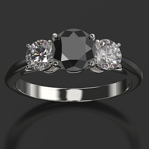 Pode incluir: Um anel de prata com tr&ecirc;s diamantes de forma oval. O diamante central &eacute; preto e os dois diamantes laterais s&atilde;o brancos.